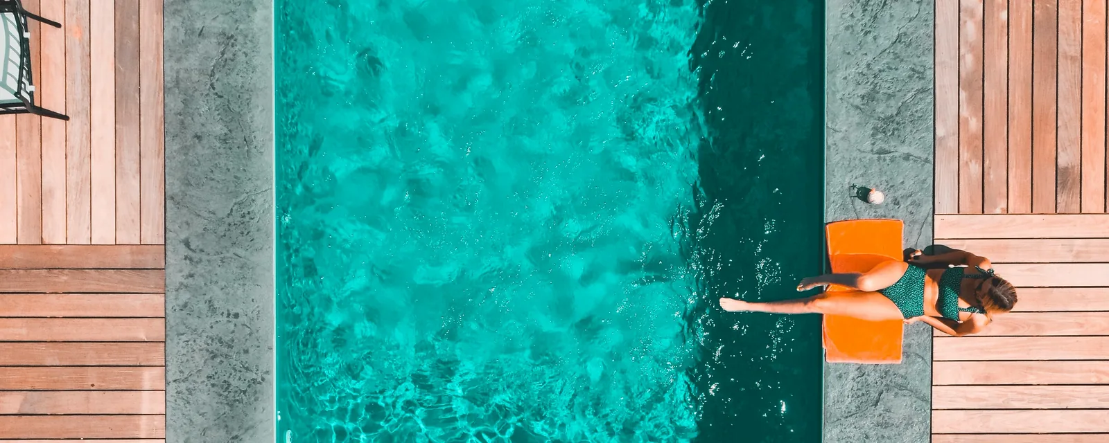 Overhead view of a compact rectangular inground pool surrounded by wood decking